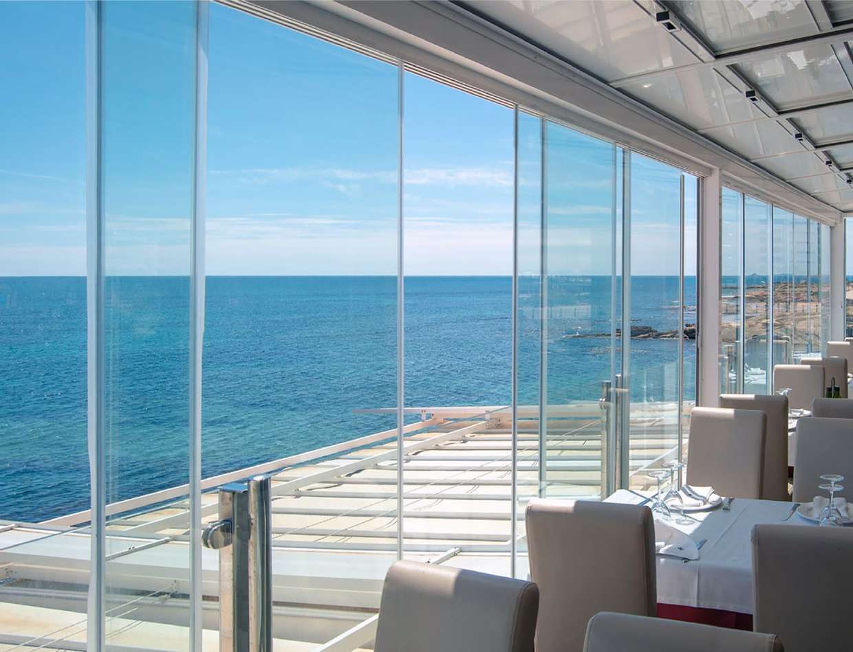 Comedor frente al mar cerrado con paneles de cristal