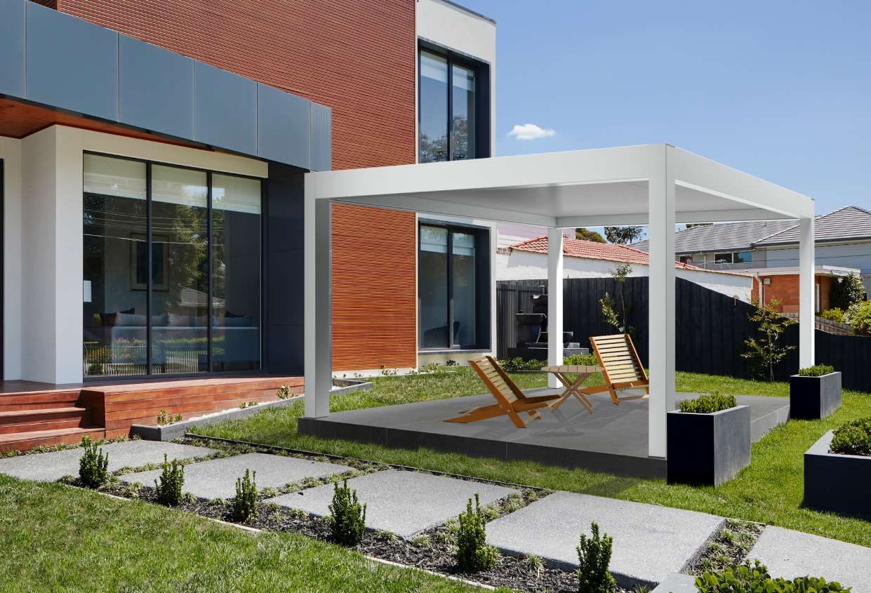 Pérgola blanca de aluminio en el jardín de una vivienda