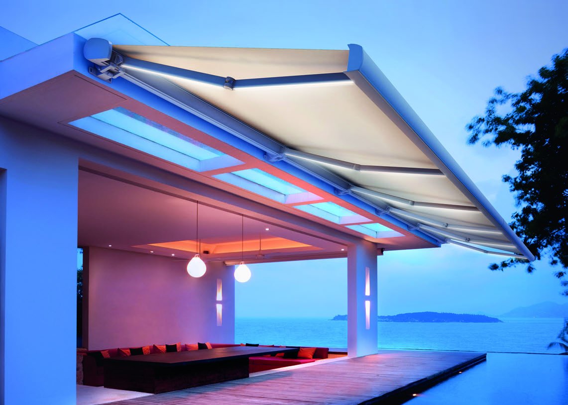 Toldo cofre multibrazo cubriendo una terraza grande al anochecer
